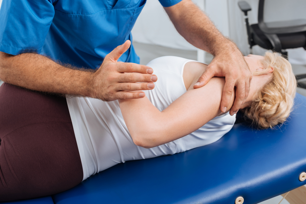 Physical Therapist assists woman in stretching exercise.